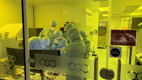 A group of scientists in a clean room gathered around an atomic force microscope for training